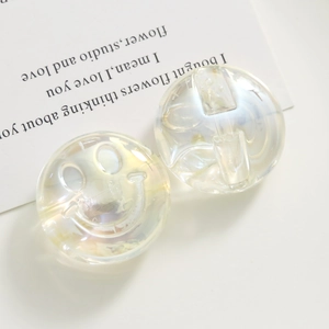 Close-up of iridescent resin M-bean charms with embossed smiley face for DIY jewelry crafts