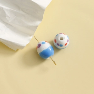 Close-up of handmade polka dot ceramic beads with golden pin for DIY jewelry making