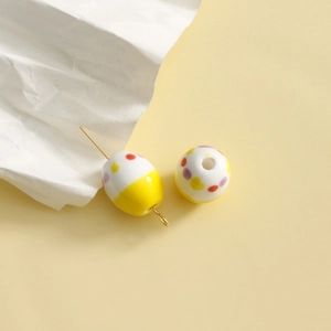 Detailed view of handmade dotted ceramic beads for DIY jewelry with gold metal pins