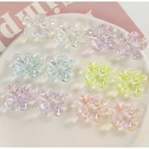 Close-up of ten iridescent resin flower charms with aurora finish on a white tray