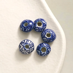 Macro detail of blue and white porcelain beads with geometric patterns in a ceramic dish