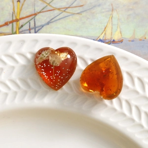 Detailed view of heart resin charms with gold leaf and dried flowers on a white plate