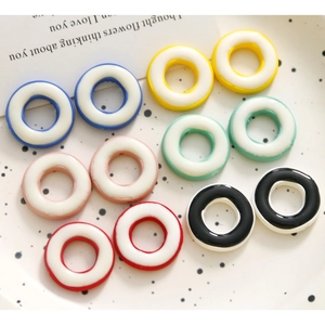 Colgantes geométricos de resina de colores para pendientes DIY sobre un plato de cerámica blanca