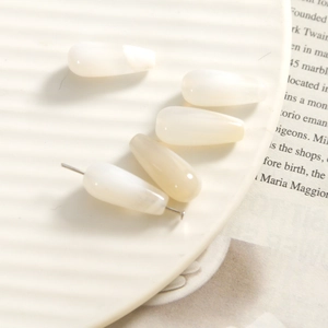 Detail of teardrop agate beads with pre-drilled holes on white ceramic tray