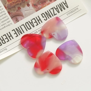 Macro detail of marbled acrylic heart charms with vibrant red and purple swirls for DIY crafts