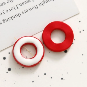 Detalle de pendientes geométricos de resina roja y blanca con diseño asimétrico
