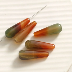 Macro detail of gradient agate teardrop beads showing pre-drilled holes for jewelry DIY