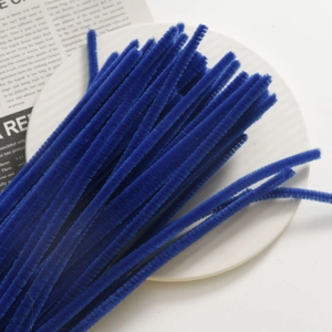 Close-up of dark blue fuzzy pipe cleaners for DIY floral crafts on a white ceramic plate