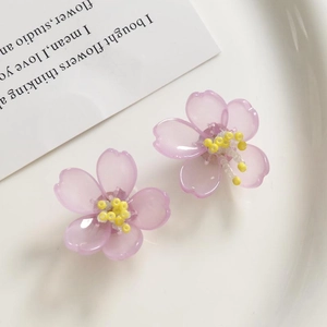 Detalle macro de pendientes de orquídea morada con estambres de cuentas amarillas