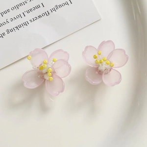 Detalle macro de pendientes de orquídea de acrílico rosa con centros de flores de cuentas