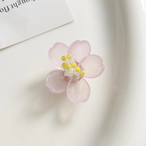 Detalle de flor de cerezo rosa de acrílico con centro amarillo sobre bandeja de cerámica