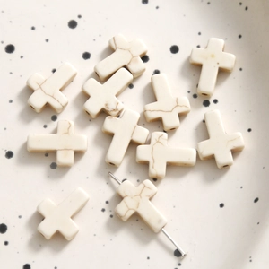 Macro detail of cross shaped white turquoise beads with natural marble texture for DIY jewelry
