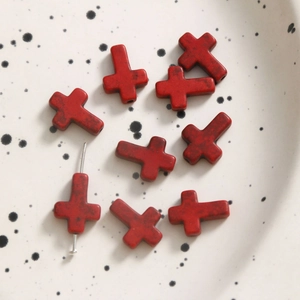 Macro shot of red cross spacer beads with vintage texture for DIY jewelry making