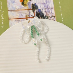 Détail des boucles d'oreilles nœud papillon irisé avec perles d'orchidée acrylique