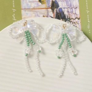 Détails des boucles d'oreilles à pompon fleuri avec nœuds blancs et perles vertes