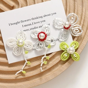 Macro view of handmade beaded flower earrings with large pearls on a wooden tray