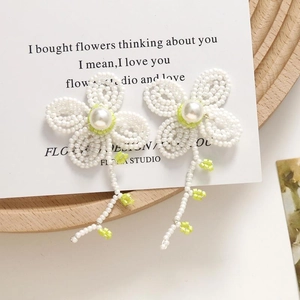 Detail of beaded flower earrings with pearl centers and long tassel pendants