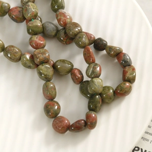 Gros plan de perles en pierre naturelle unakite aux motifs vert et rouge sur céramique