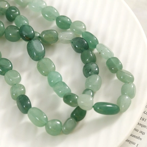 Gros plan de perles ovales en aventurine verte naturelle sur une assiette en porcelaine