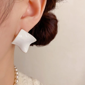 Close-up of white irregular geometric stud earrings with glossy finish on a model