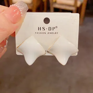 Close-up of white irregular enamel square studs with gold edges on S925 silver needles