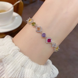 Détail d'un bracelet en argent avec zircons colorés porté sur une manche en dentelle