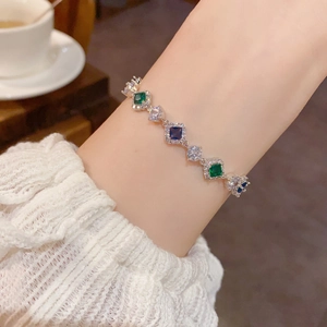 Gros plan d'un bracelet en argent avec zircons colorés au poignet d'une femme
