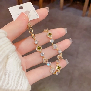 Détail du bracelet doré orné de zircons carrés verts et de cristaux blancs avec étiquette