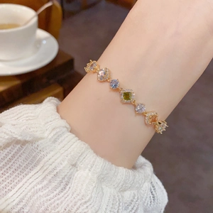 Gros plan d'un bracelet doré avec des pierres de zircon colorées sur le poignet