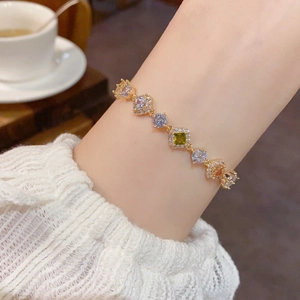 Bracelet élégant doré avec des pierres de zircone colorées sur le poignet d'une femme