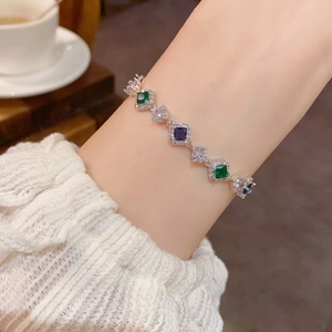 Détail d'un bracelet en argent avec zircons colorés porté sur un poignet en dentelle