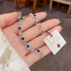 Détail du bracelet argenté avec pierres vert émeraude et bleu saphir bleu ornées de pavé de zircons