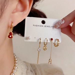 Detailed view of red gourd pendants and pearl chain earrings set in gold finish