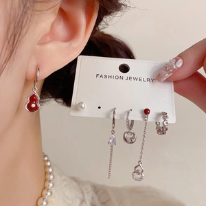 Detail of red gourd earrings set with pearls and tassels shown on a display card