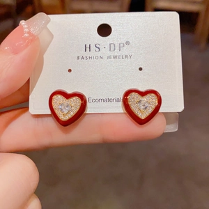 Détail de boucles d'oreilles cœur rouge avec bordure dorée et pavé de zircons