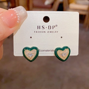 Gros plan de boucles d'oreilles cœur en émail vert foncé et zircons sur carte bijoux