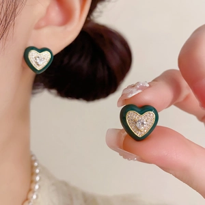 Gros plan détaillé de boucles d'oreilles cœur vert foncé avec bordure dorée
