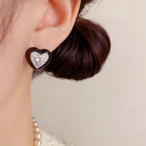 Gros plan sur boucle d'oreille cœur noir et blanc avec cristaux scintillants sur modèle