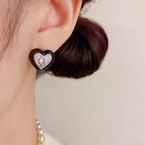 Gros plan de boucles d'oreilles cœur en émail noir avec zircons blancs scintillants