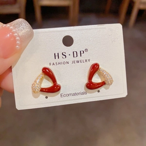 Détail de boucles d'oreilles triangulaires avec émail rouge et zircon sur carte