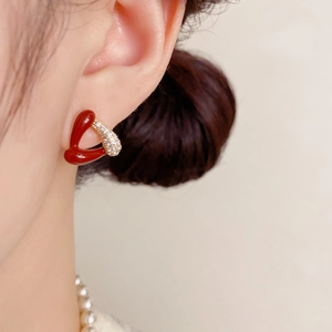 Détail d'une boucle d'oreille cœur en émail rouge avec zircons sur le lobe
