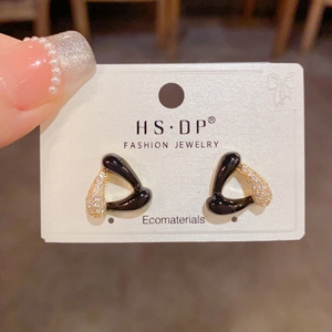 Détail macro de boucles d'oreilles triangles en émail noir et zircons sur support