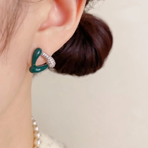 Gros plan d'un modèle portant des boucles d'oreilles triangle en émail vert et zircons