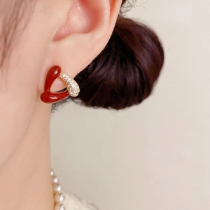 Détail d'une boucle d'oreille cœur en émail rouge et zircone sur un mannequin