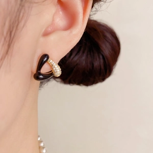Gros plan sur la boucle d'oreille géométrique en émail noir et or avec zircons