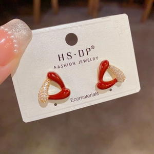 Détail de boucles d'oreilles triangles en émail rouge avec zircone portées à la main