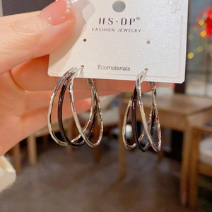 Detail of multi-layered silver and black enamel intertwined hoop earrings for women