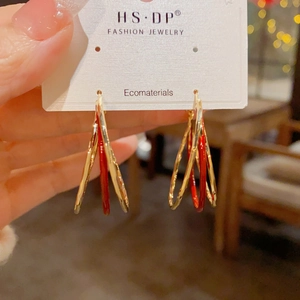 Detailed view of triple-layered gold and red enamel earrings on a display card