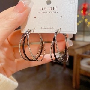 Detail of multilayered black and silver interlocking hoop earrings on branded display card
