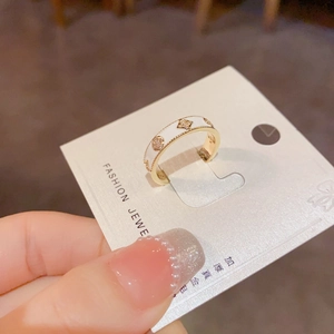 Détail macro d'une bague fleur à quatre feuilles dorée avec émail blanc et étoiles